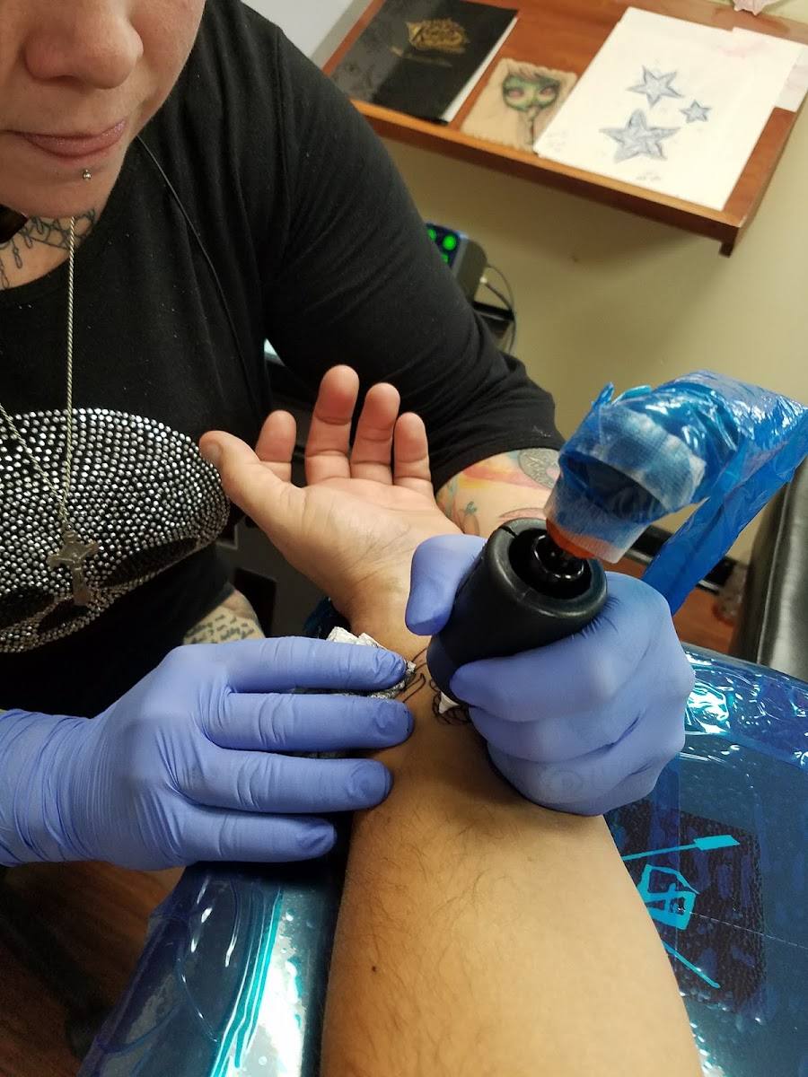 Artist in blue gloves tattooing a client